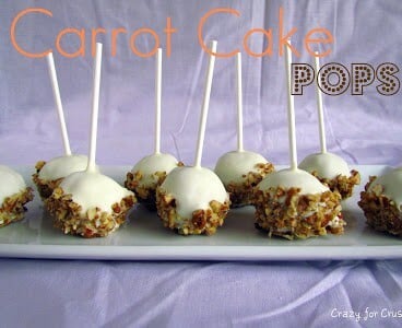 carrot cake pops covered in white chocolate and pecans with sticks sticking up on purple background