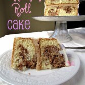 cinnamon roll cake slice on white plate with cake behind on platter
