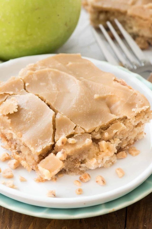 Apple Toffee Bars on a white plate with cracked caramel frosting and fork behind