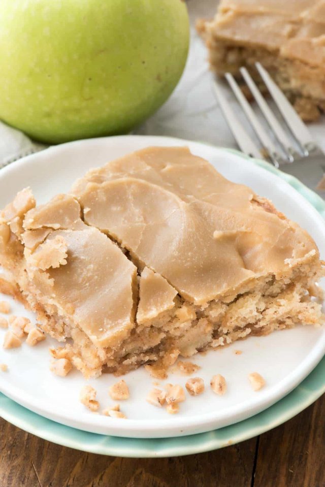 Apple Toffee Bars on a white plate with cracked caramel frosting and fork behind