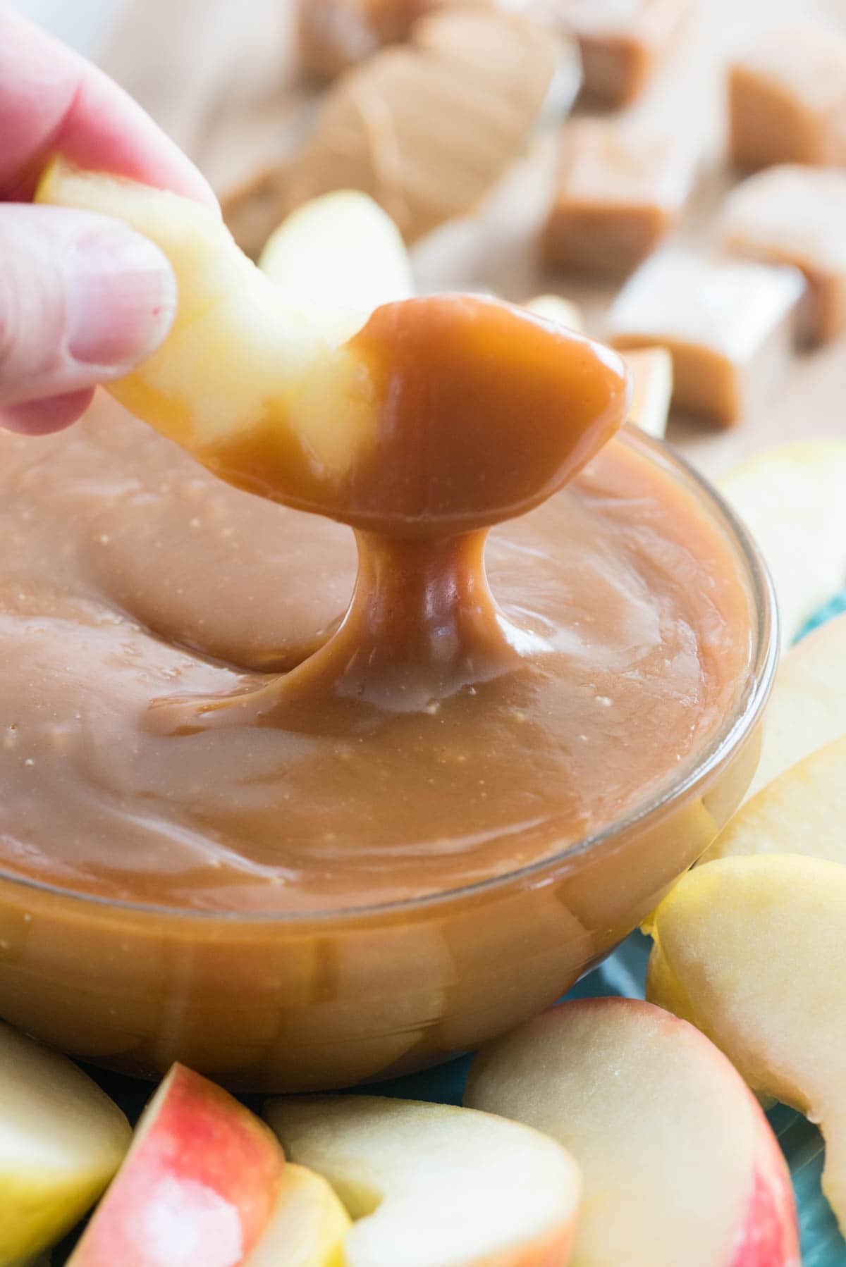 peanut butter caramel apple dip with apple slice being held by hand