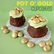 two cupcakes dipped in chocolate with green frosting and gold colored candy to look like pot o gold cupcakes