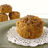 Pumpkin bran muffins on a white doily and green plate with three additional muffins in the background.