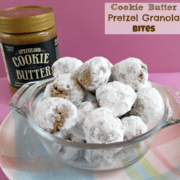 cookie butter pretzel granola bites in a clear bowl on top of a pastel plate with the cookie butter jar in the background and the graphic title in the top right hand corner