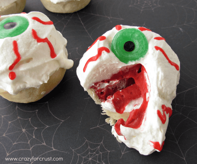 Red Velvet Eyeball Pies with whipped cream and red frosting eyes with lifesaver pupils cut open to see inside