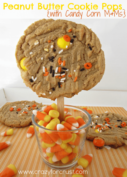 peanut butter cookie pops with halloween sprinkles on a stick in a dish of candy corn