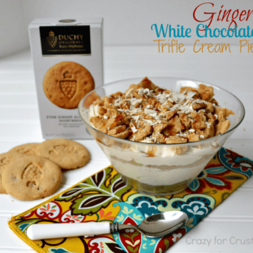 ginger white chocolate trifle in a trifle dish with printed napkin underneath and spoon, and ginger cookies