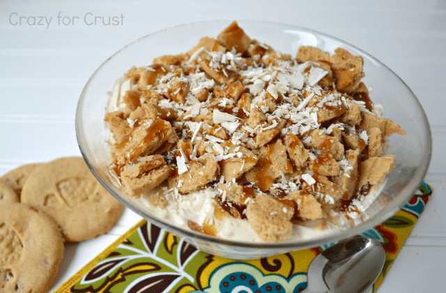 ginger white chocolate trifle in a trifle dish with printed napkin underneath and spoon, and ginger cookies