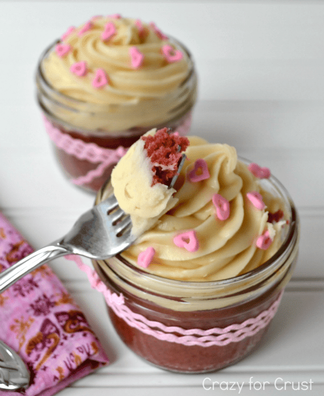 pink velvet cupcakes in jars with cream cheese frosting and pink heart sprinkles, wrapped with a pink bow with words on photo