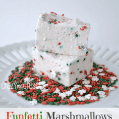 Two Funfetti marshmallows on top of Christmas colored sprinkles on a white plate, graphic image on the bottom.