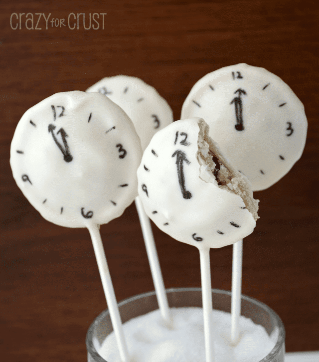 clock pie pops with white chocolate coating and clock face drawn on them one with bite missing