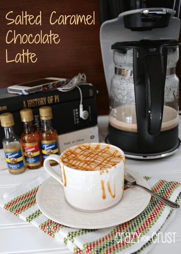 salted caramel chocolate latte in a white mug with coffee maker behind