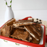 Peanut butter chocolate toffee bark in a red and white bowl, with glass jar holding straws in the background.