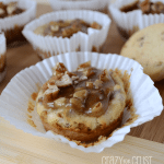 Pecan praline cheesecakes in white cupcake liners on a wooden board.
