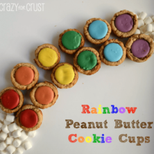 Rainbow peanut butter cookie cups in the shape of a rainbow with mini marshmallows at the end, graphic title on the bottom right.