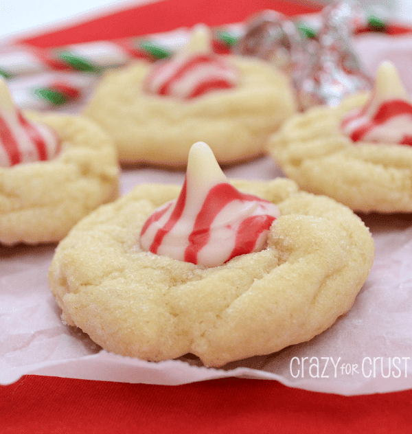 Four Triple White Chocolate Peppermint Blossom cookies on white parchment paper with red underneath
