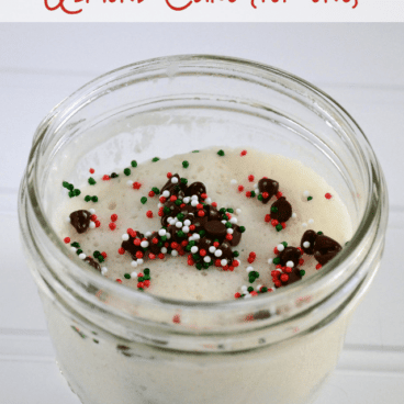 Almond cake for one in a mason jar, topped with chocolate chips and holiday sprinkles, graphic title on the top.