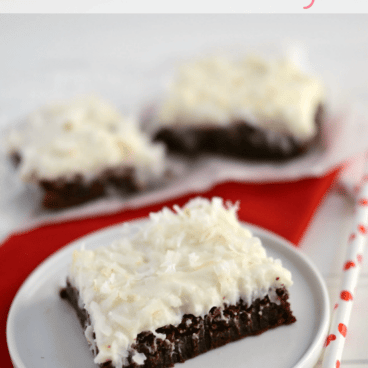 fudgy brownies with coconut frosting on white plate with straw and red napkin