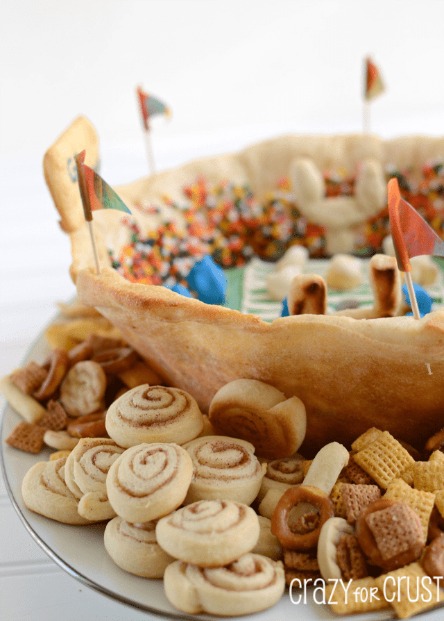 Snackadium made out of crescent rolls with icing field and sprinkle people on white plate with pie crust and cracker dippers