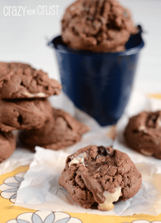 chocolate pb pudding cookies on parchment paper with marshmallows spilling out