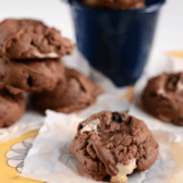 chocolate pb pudding cookies on parchment paper with marshmallows spilling out