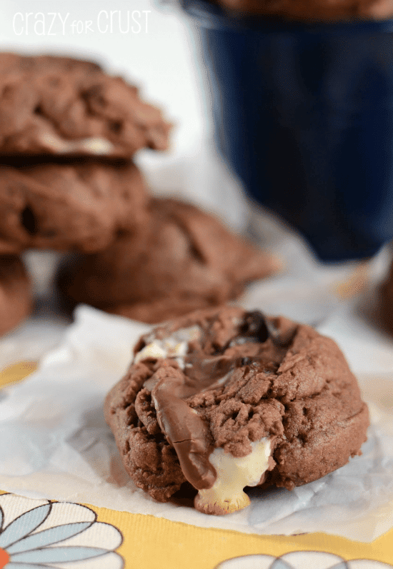 chocolate pb pudding cookies on parchment paper with marshmallows spilling out