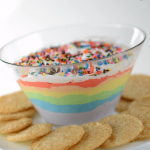 rainbow dip with cookies around on cake plate with words