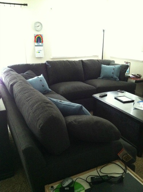 Photo of the new sectional couch that is dark grey with blue pillows