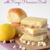 lemon bars in a stack on cutting board with rolls behind and lemon and words on photo