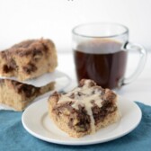 Mocha Coffee Cake piece on a white plate with blue napkin and more coffee cake and coffee in the background