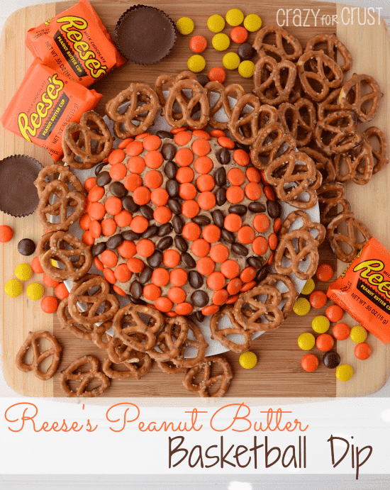 Overhead shot of Reeses Basketball Dip with pretzels and candy scattered around plate and recipe title on bottom of image