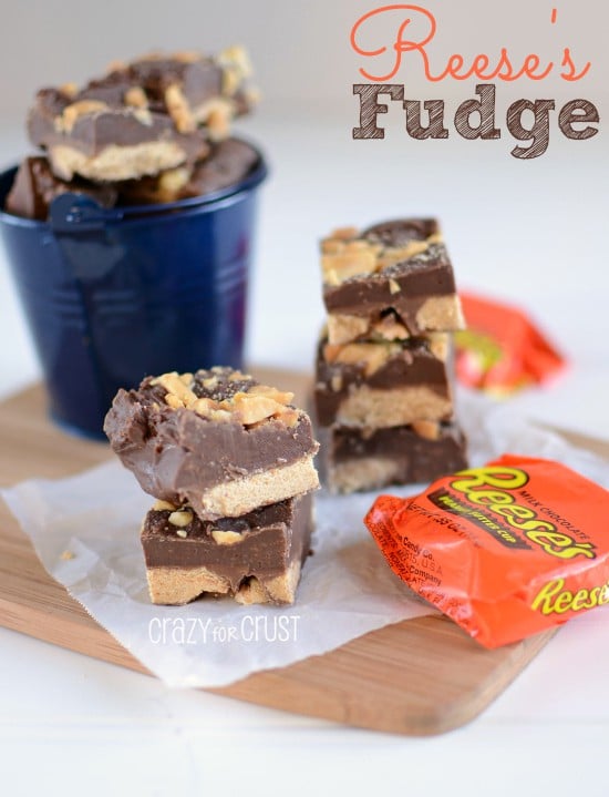 Reese's Fudge stacked on top of parchment paper and wood cutting board with reeses cups and recipe title on top right corner of photo