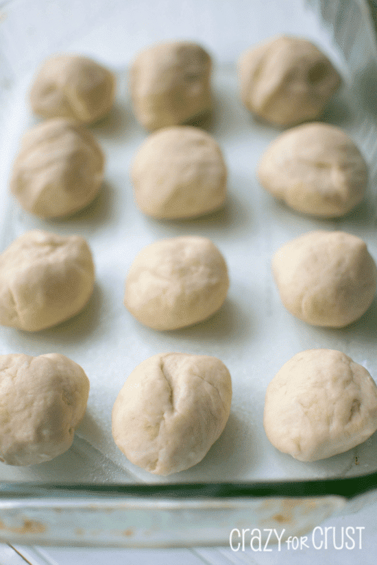 Dinner rolls in dough balls in glass baking dish