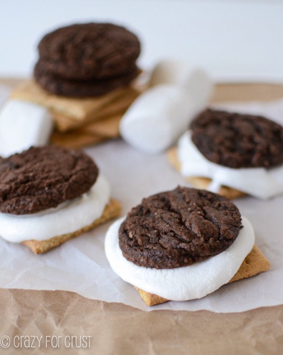 brownie cookie sandwiched with melted marshmallow and graham cracker on parchment paper