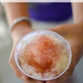 girl holding snow cone that is pineapple upside down cake flavor