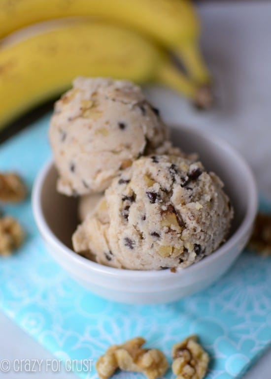 healthy banana nut ice cream in white bowl on teal napkin with bananas behind