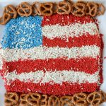 peanut butter dip made to look like a flag with red white and blue sprinkles and pretzels around it on white background