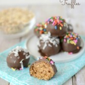 peanut butter oatmeal truffles coated in chocolate on white plate and teal napkin with one truffle cut in half and words on photo