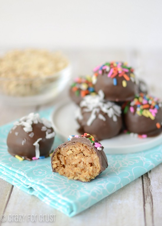 peanut butter oatmeal truffles coated in chocolate on white plate and teal napkin with one truffle cut in half 