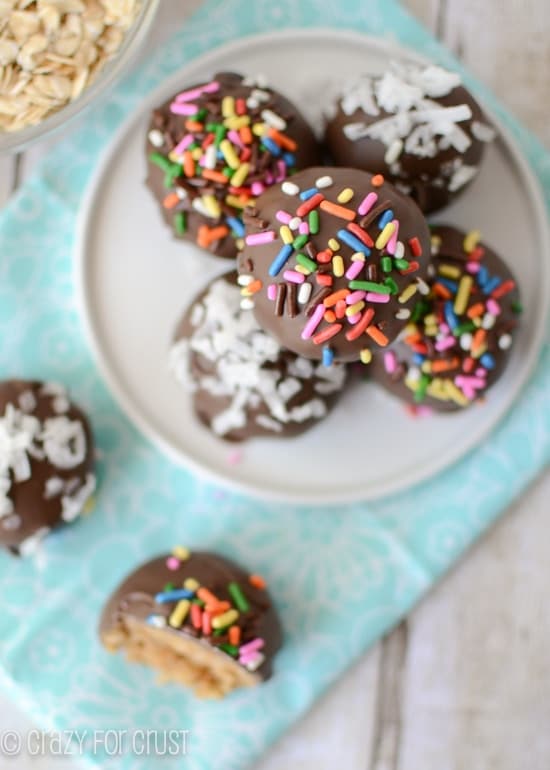 peanut butter oatmeal truffles coated in chocolate on white plate and teal napkin with one truffle cut in half overhead shot