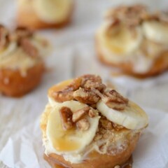 fried doughnut on parchment paper topped with bananas nuts and caramel