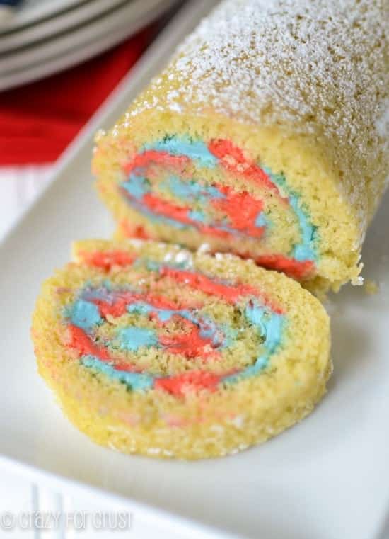 Patriotic Cake Roll with one slice laying on its side on a white platter