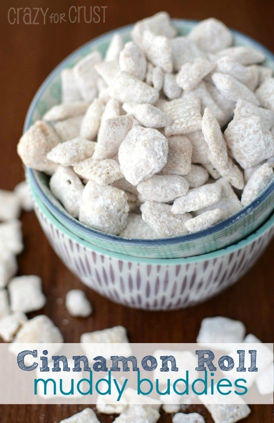 cinnamon roll muddy buddies coated in powdered sugar in two bowls on brown table