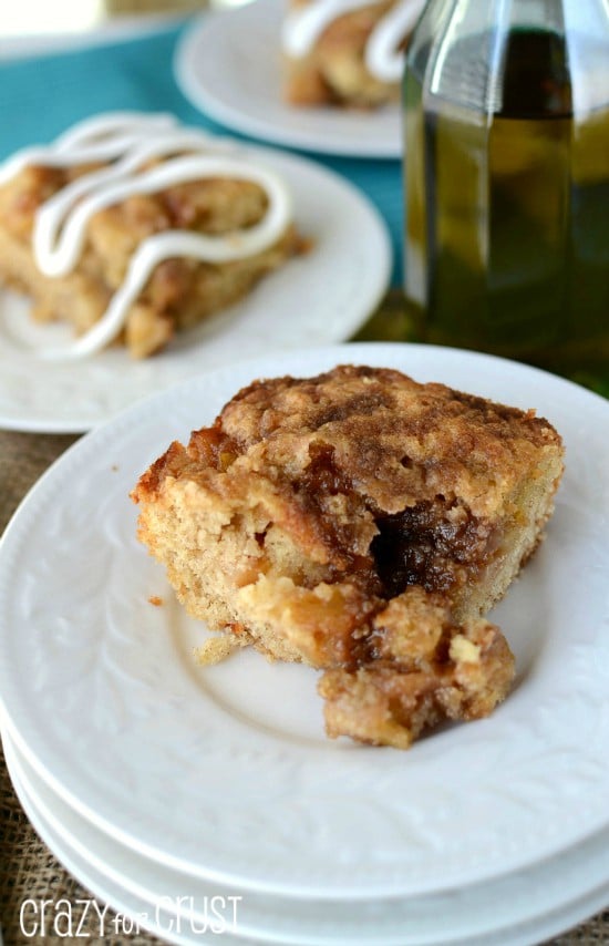 slice of cinnamon zucchini coffee cake on stack of white plates with olive oil bottle behind