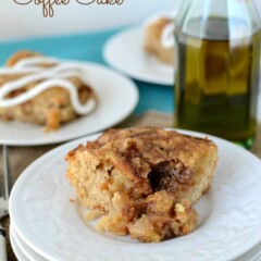 slice of cinnamon zucchini coffee cake on stack of white plates with olive oil bottle behind