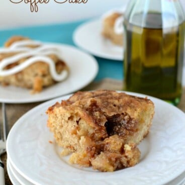 slice of cinnamon zucchini coffee cake on stack of white plates with olive oil bottle behind
