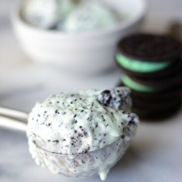 green mint ice cream with oreos inside in a ice cream scoop on marble slab