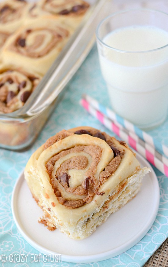 peanut butter cinnamon roll on white plate with teal napkin and pan of rolls behind