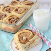 peanut butter cinnamon roll on white plate with teal napkin and pan of rolls behind