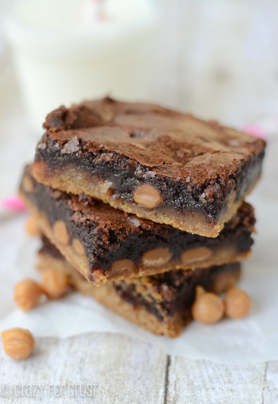 Stack of three Caramel Brownie Peanut Butter Cookie Bars on white wood table
